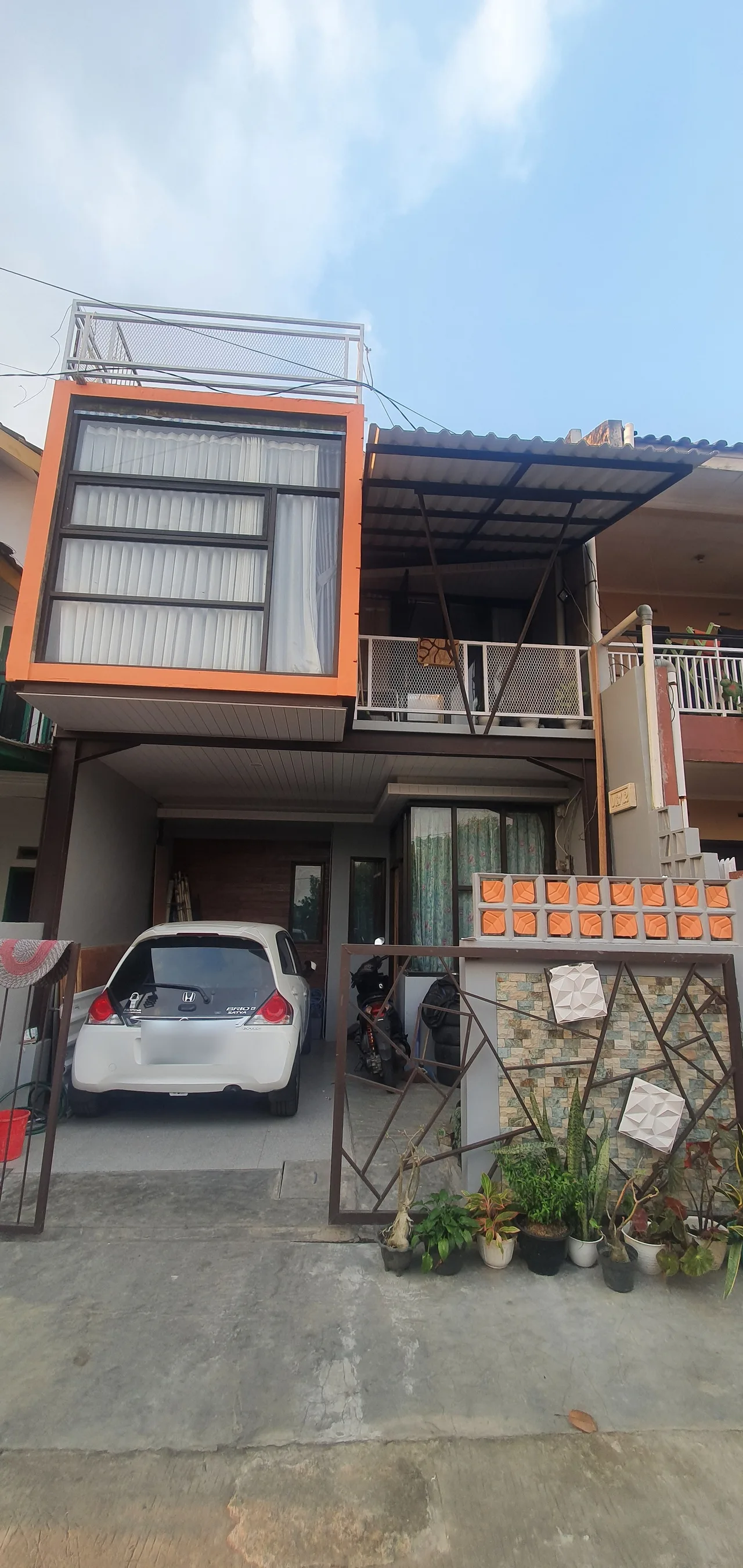 Rumah selesai direnovasi jadi dua lantai, fasad oranye dengan carport